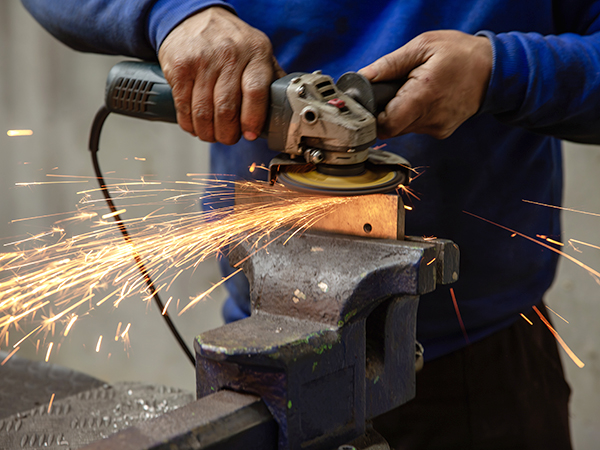 Heavy industry worker cutting steel with an angle grinder.